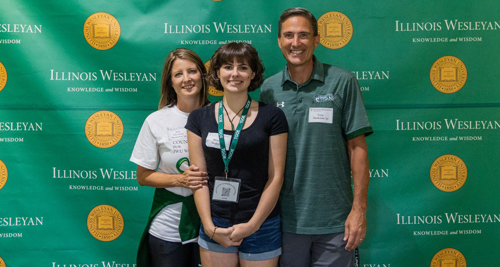 The Bankston family stands in front of an Illinois Wesleyan University backdrop and smiles at the camera