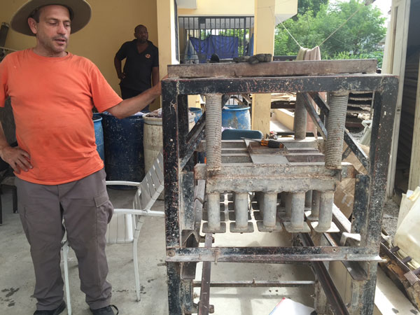 Kevin Hineline ‘88 showcases one of the hand-operated recycled briquette presses used by Fuego del Sol in Haiti.