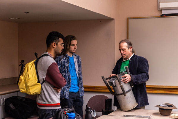 Kevin shows one of the old stove designs used by Fuego del Sol to IWU physics students working on creating a new design.