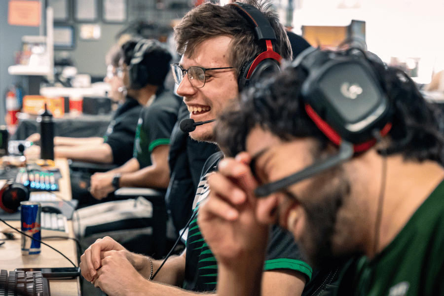 esports students laugh together at computers with headsets