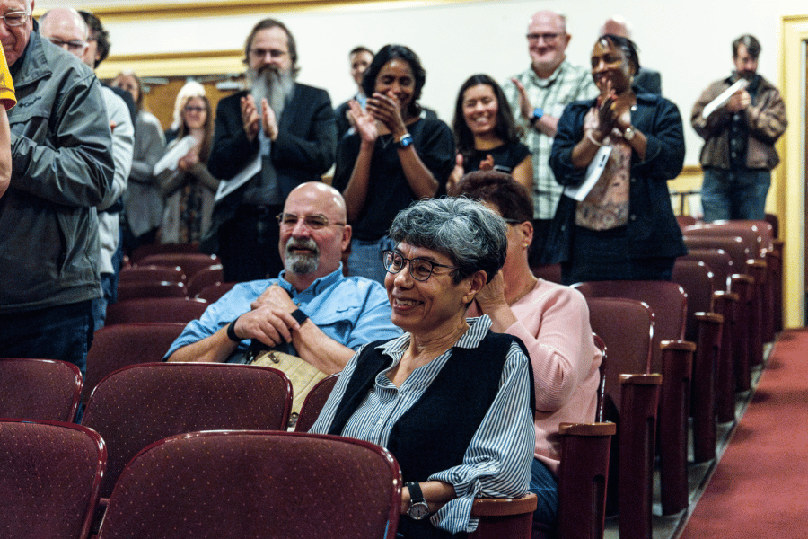 Zahia Drici Zahia Drici seated in auditorium as audience stands and applauds around her