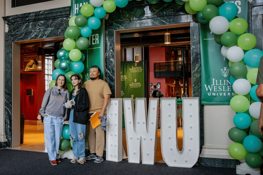new students Student with family standing in front of IWU sign and balloons
