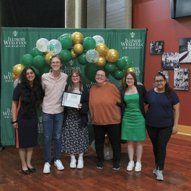 students stand by balloons with award
