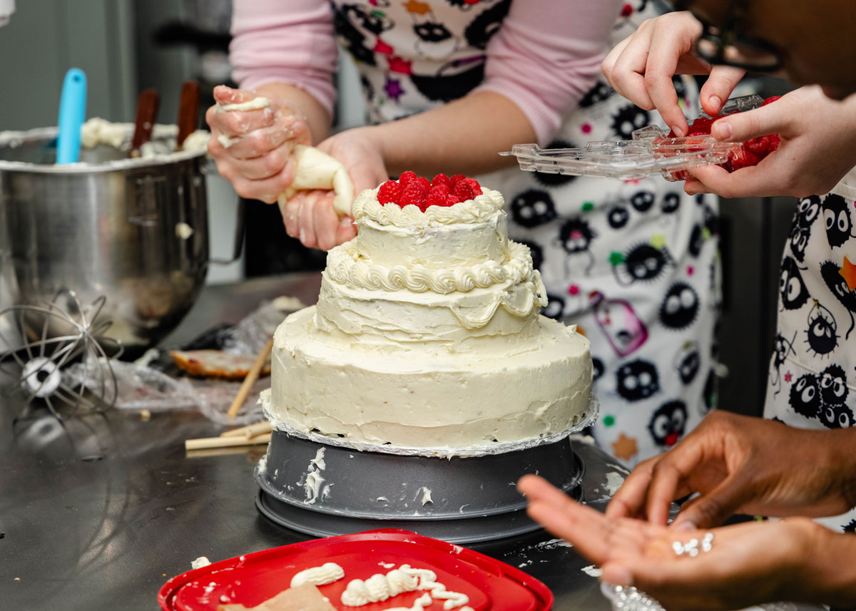  All hands on deck for the final decor on the wedding cake.