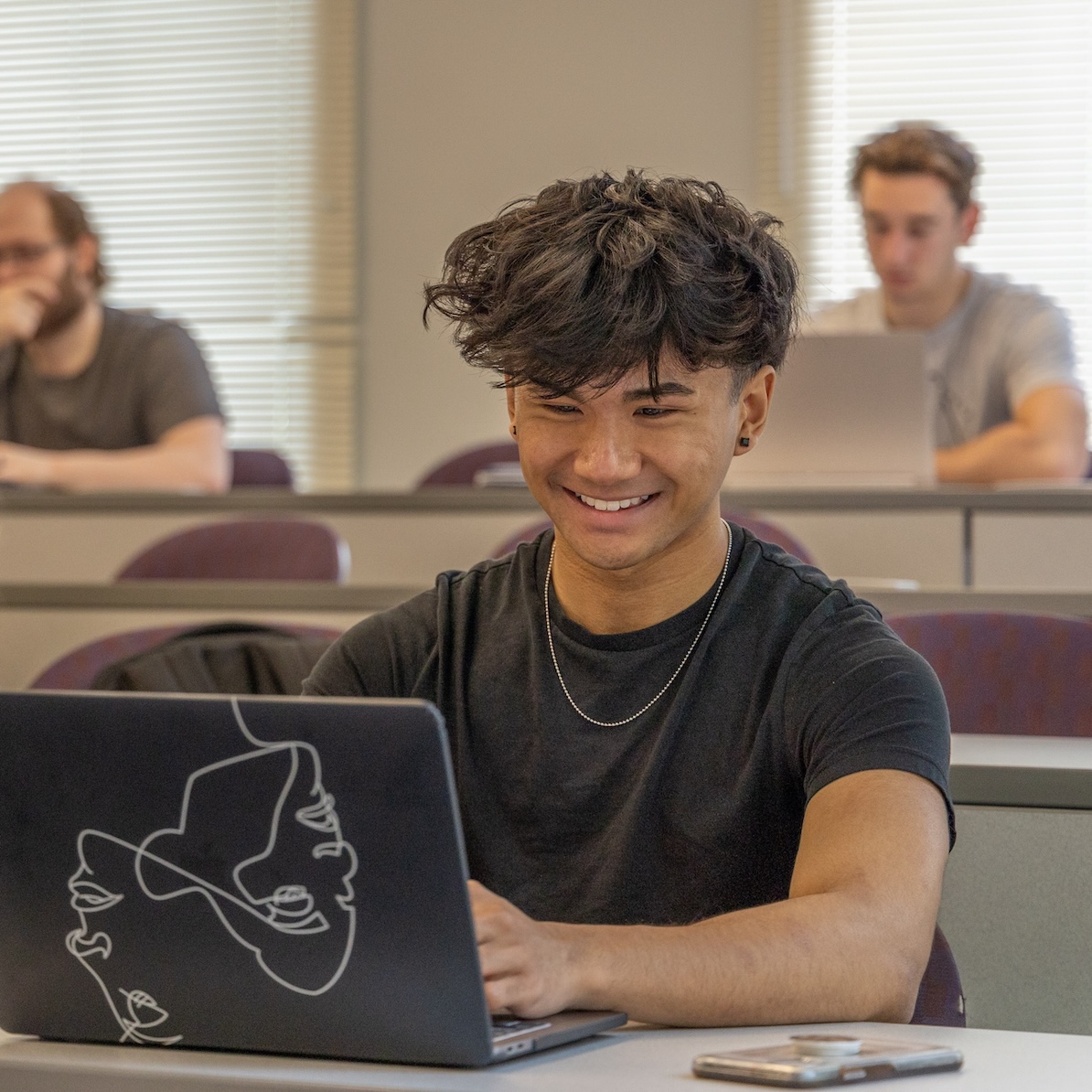 Students working in the classroom on laptops.